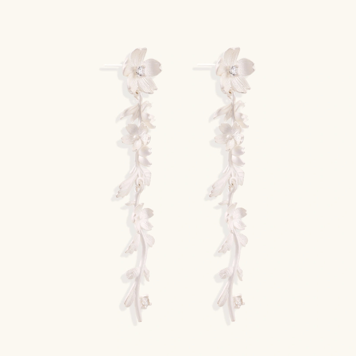 Long sterling silver drop earrings with delicate floral vine design and crystal accents on white background