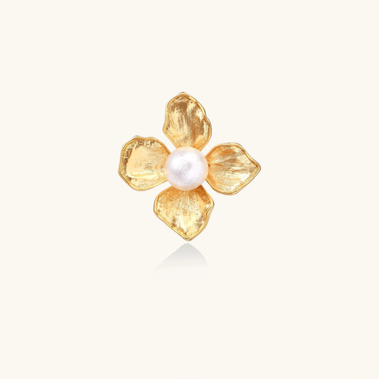Gold-plated flower ring with textured petals and white cotton pearl center on cream background