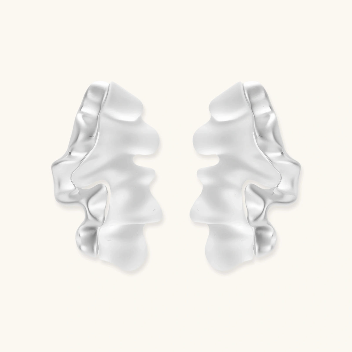 Pair of silver-toned sculptural earrings with flowing abstract forms and stud backs against white background.